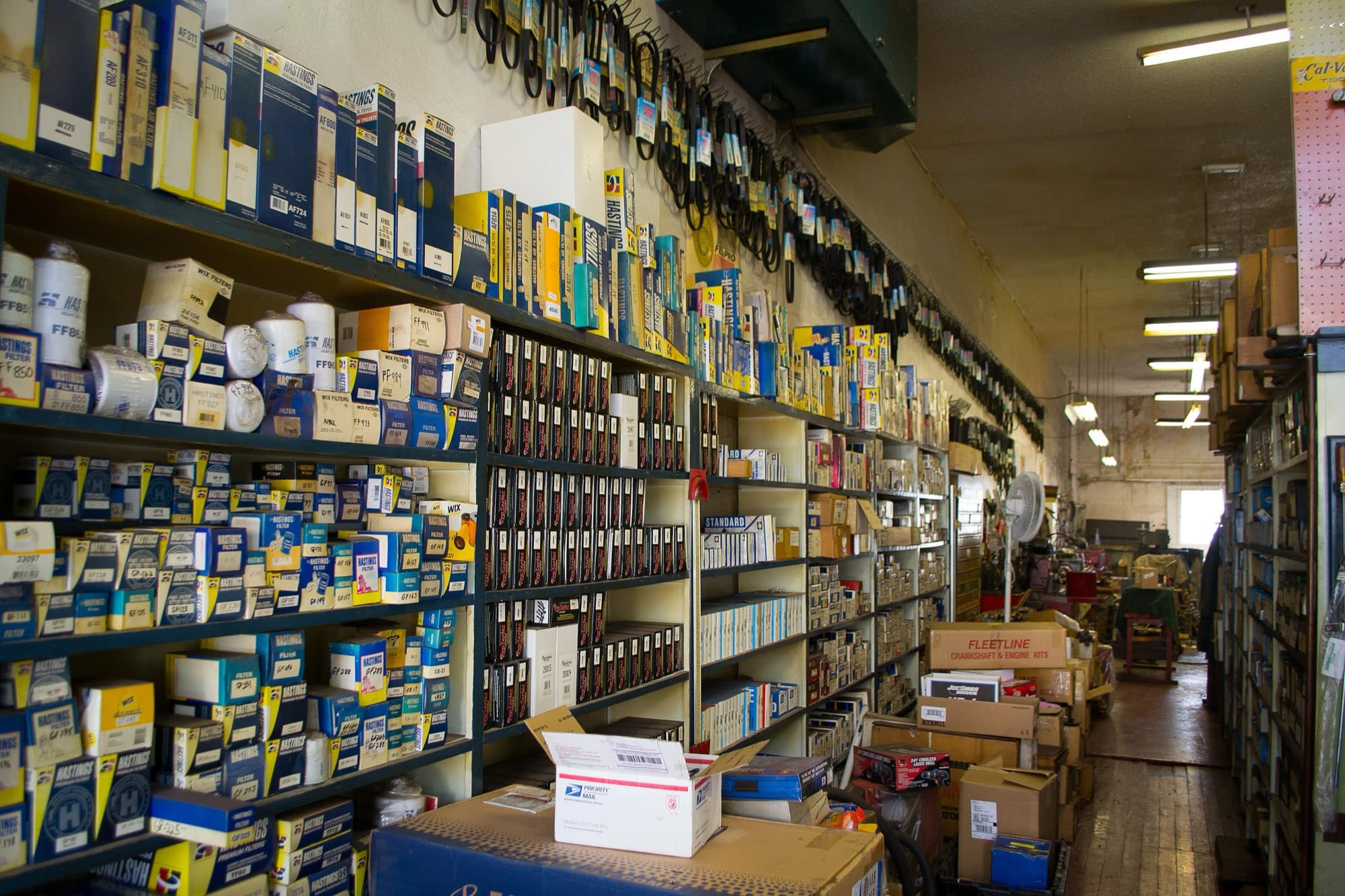 Long shelves packed with boxed filters, drive belts and engine parts in a spare-parts store.