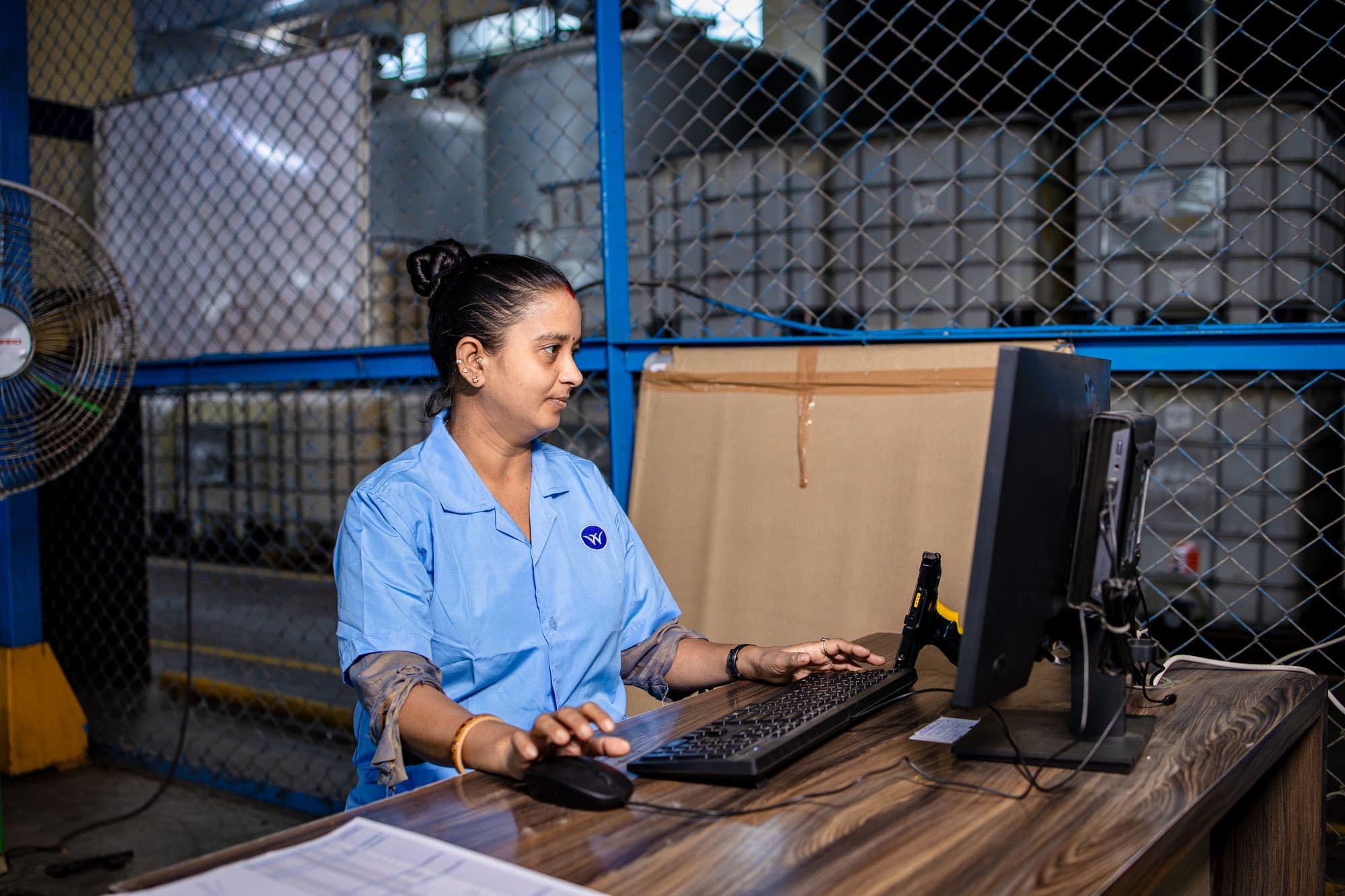 A warehouse staff member at a computer desk processing parts orders.